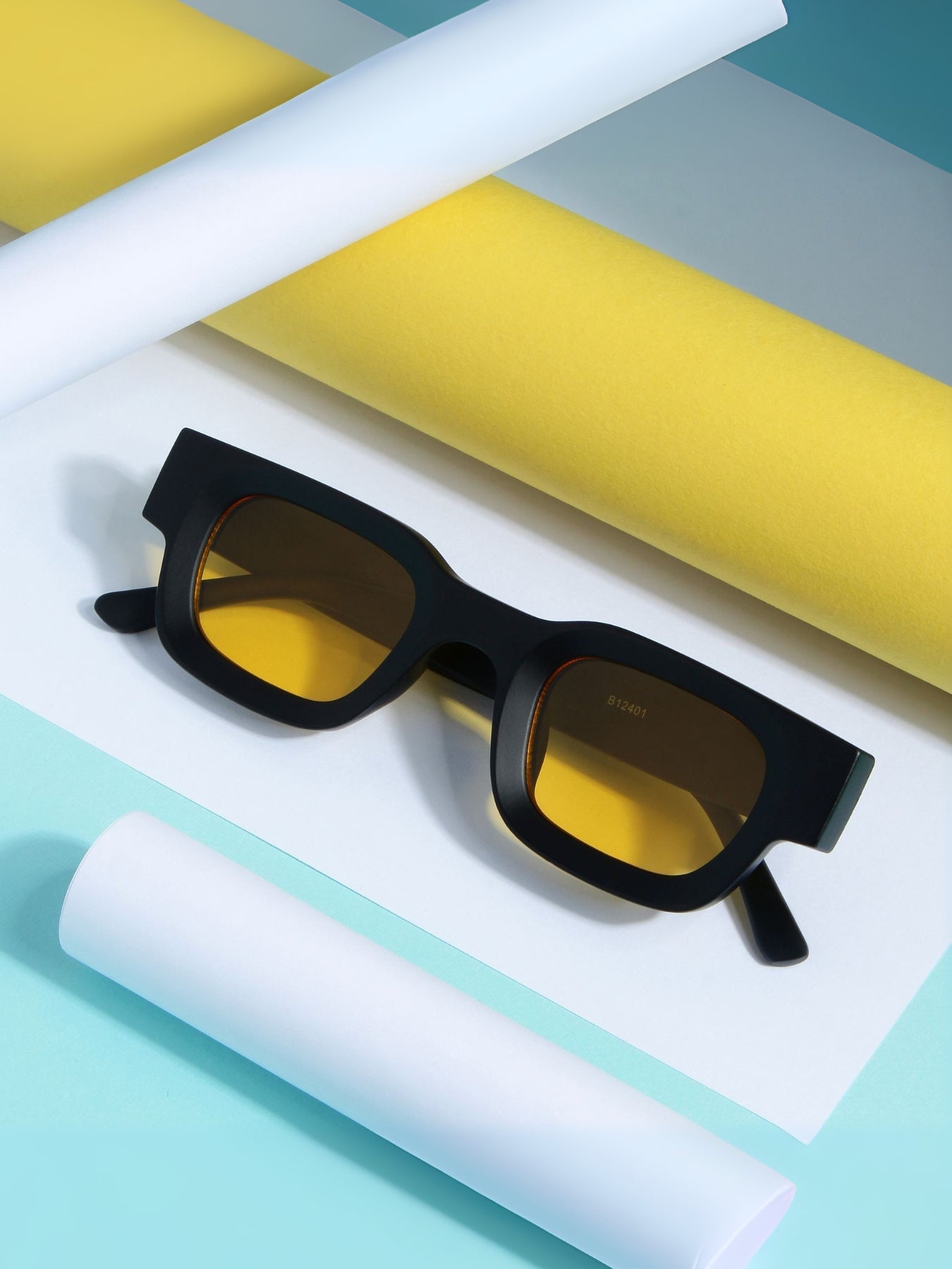 Black sunglasses with yellow lenses on a white and yellow striped surface