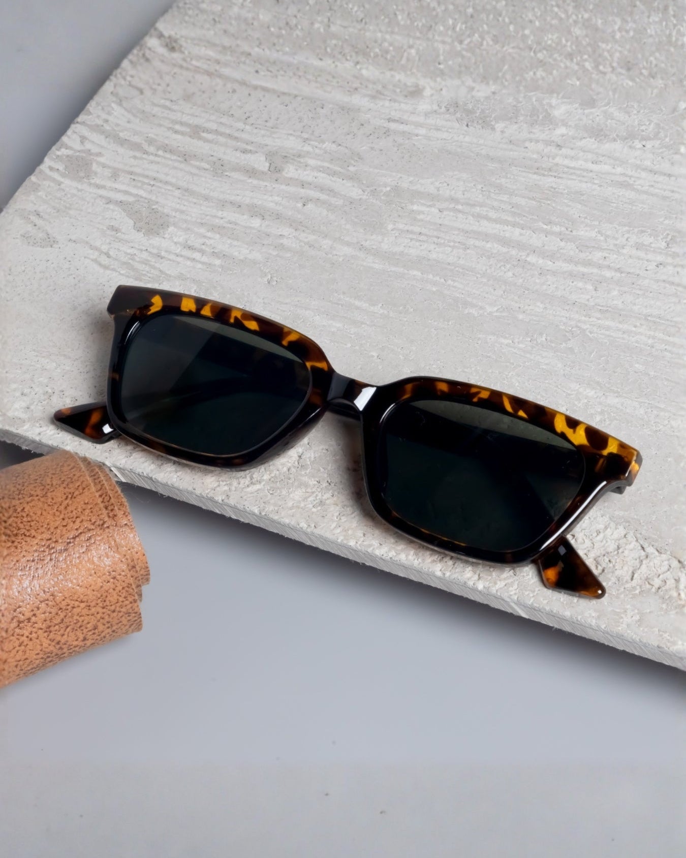Sunglasses with tortoiseshell frame on a textured surface