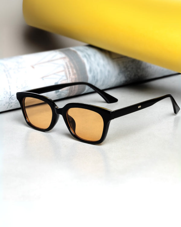 Sunglasses with black frame and yellow-tinted lenses on a white surface.