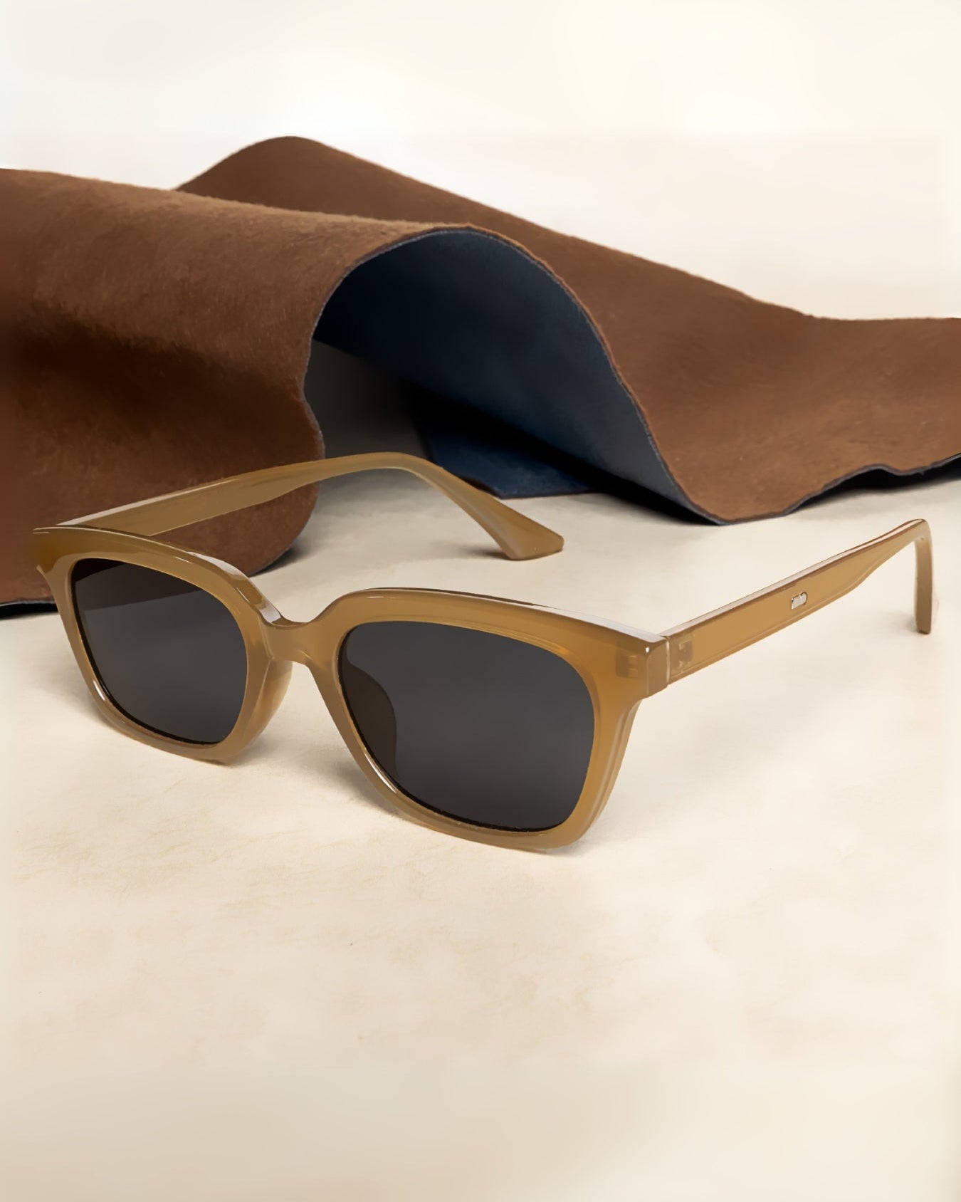 Sunglasses with brown frame and dark lenses on a light beige background