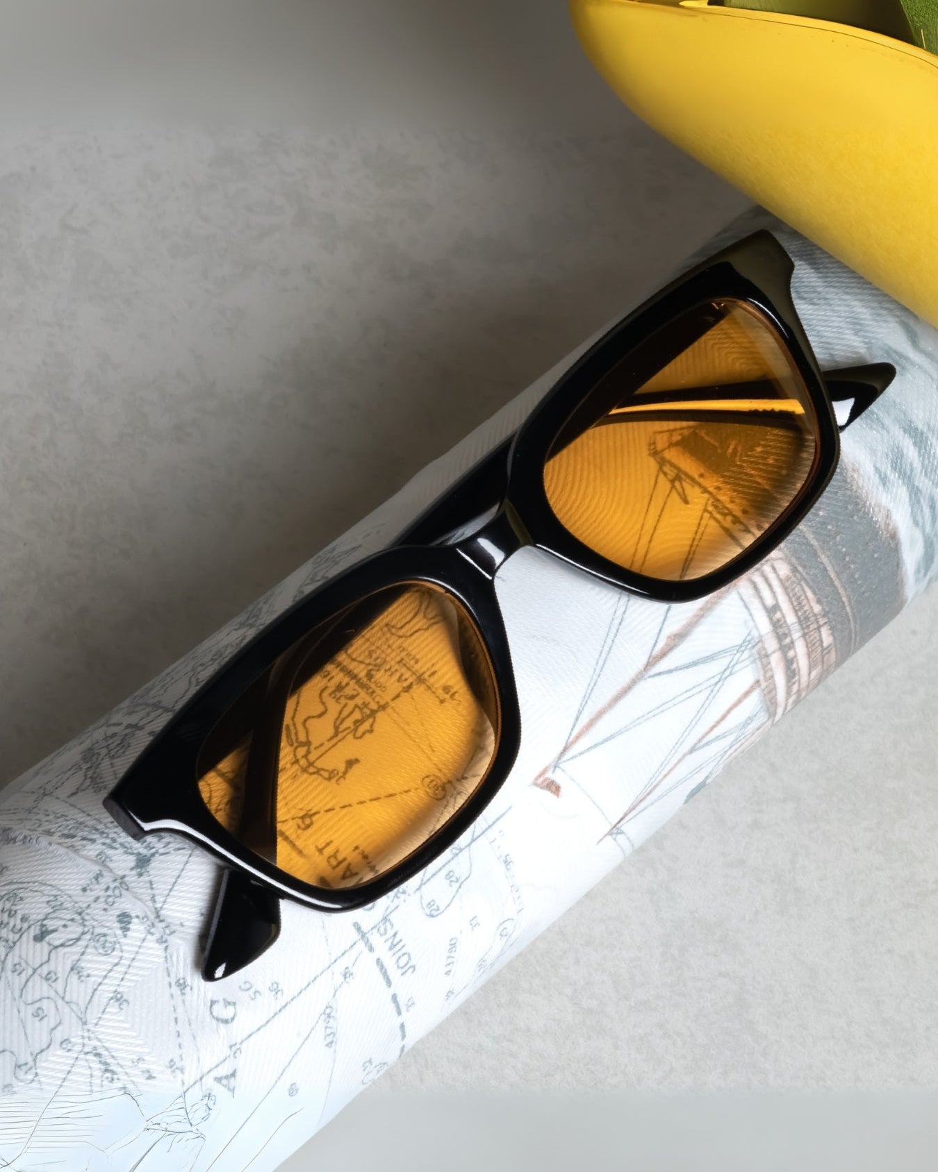 Black-framed sunglasses with yellow lenses on a map