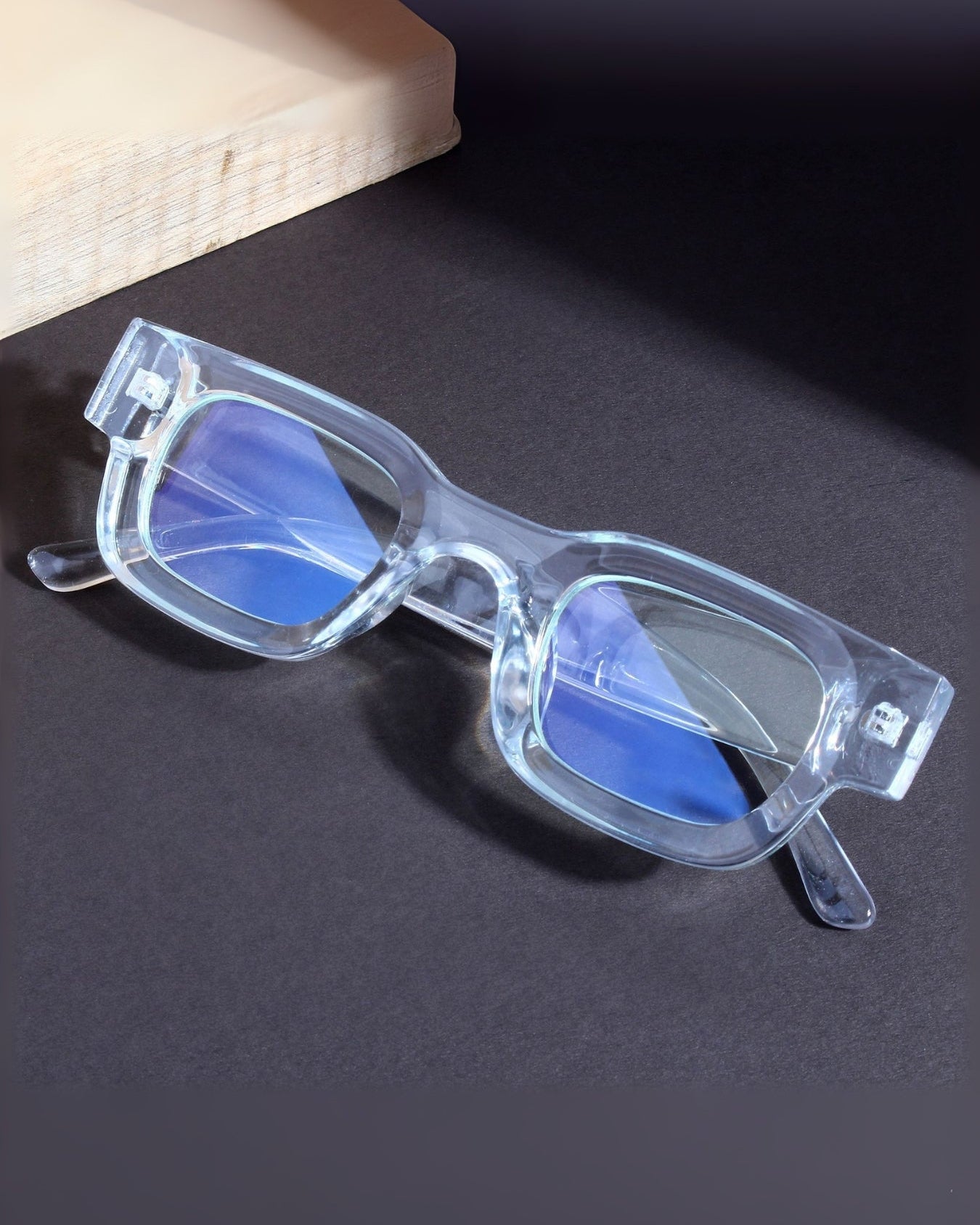 Clear sunglasses with blue lenses on a dark surface