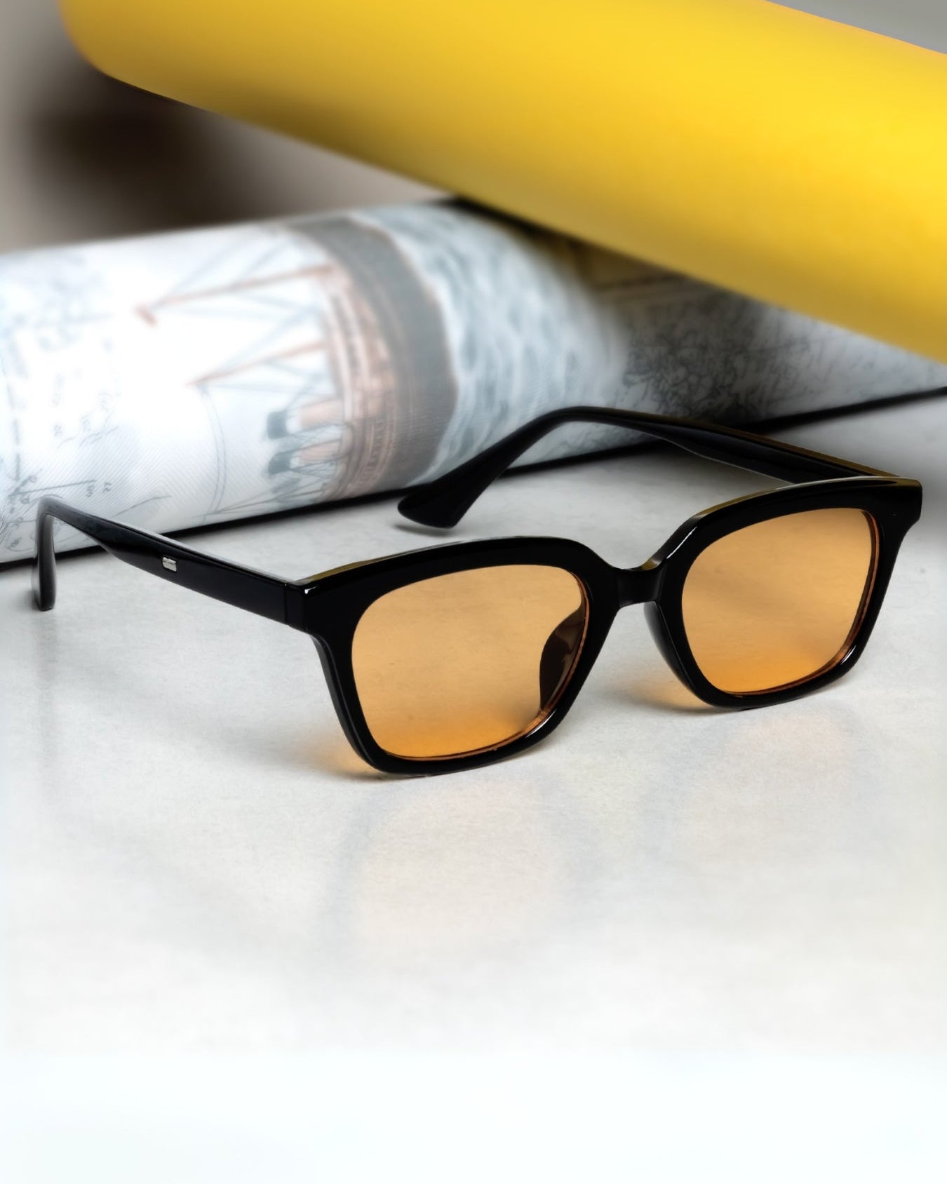 Sunglasses with yellow-tinted lenses on a white surface