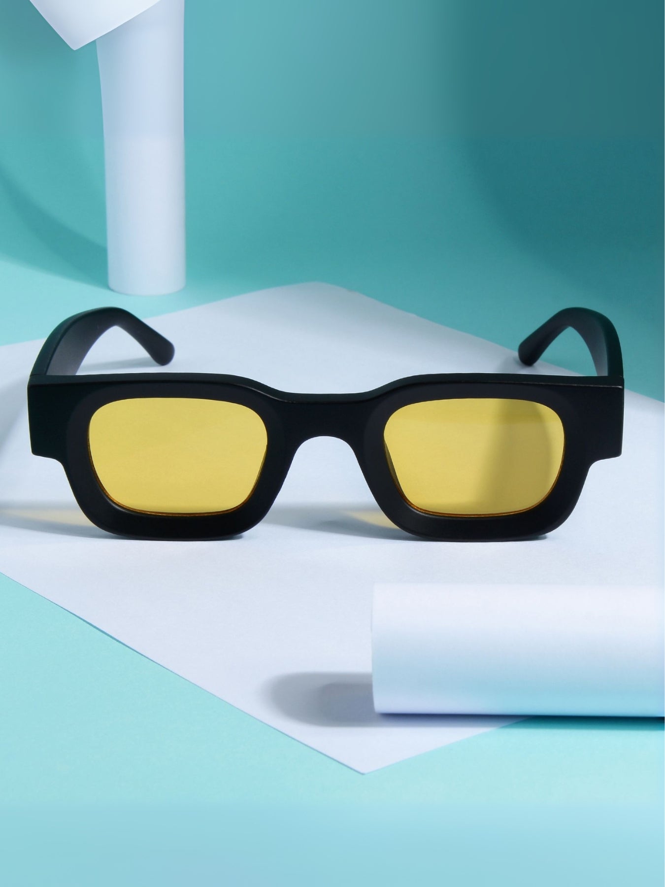 Black sunglasses with yellow lenses on a light blue background