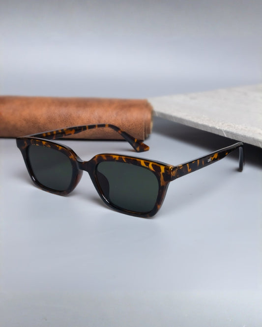 Sunglasses with tortoiseshell frame and dark lenses on a light gray surface.
