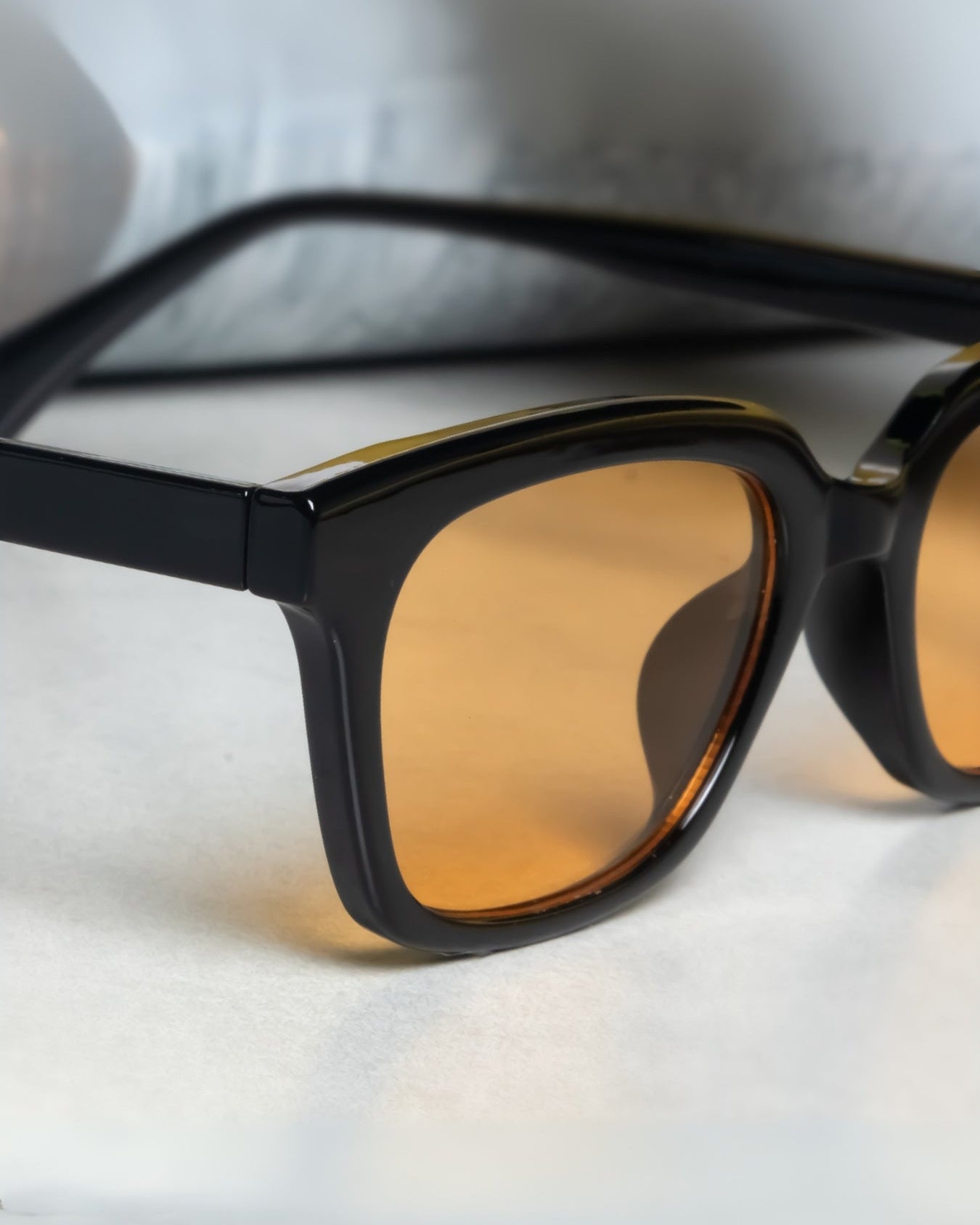 Black-framed sunglasses with brown lenses on a white surface