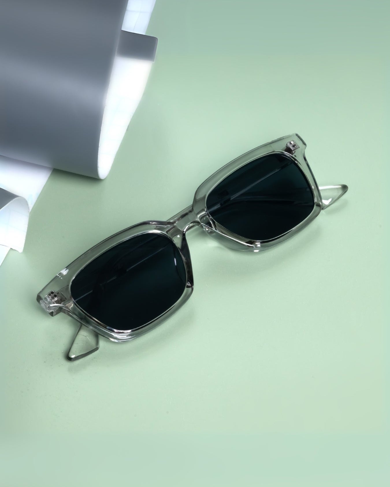 Sunglasses with a metallic frame on a light green surface