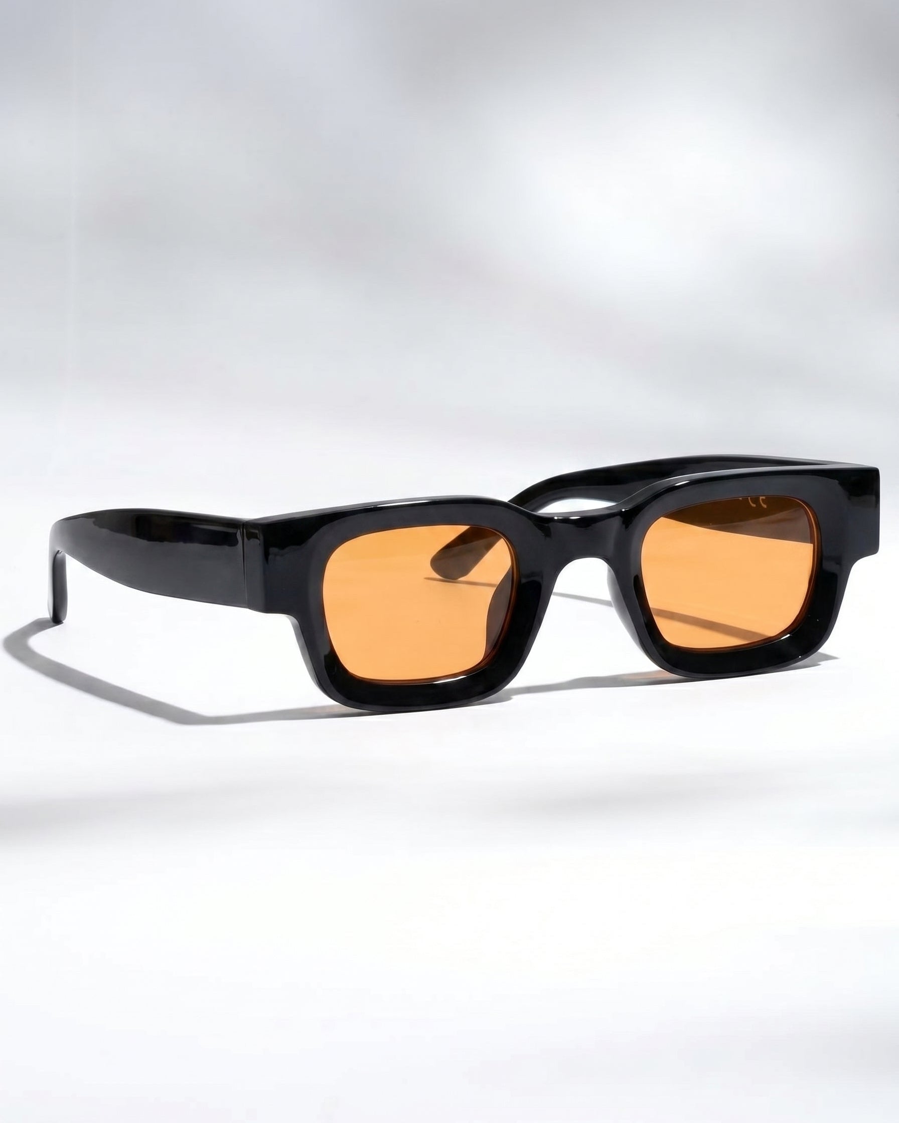 Black sunglasses with orange lenses on a white background
