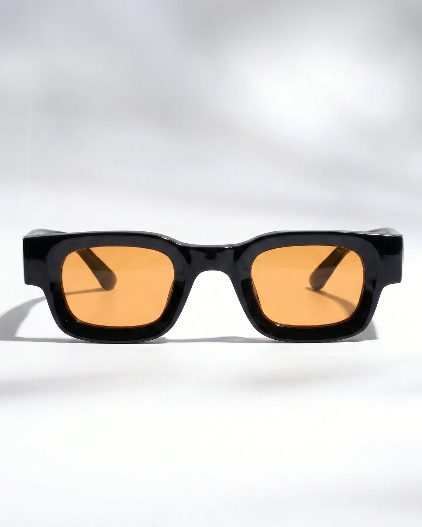 Sunglasses with black frame and orange lenses on a white background