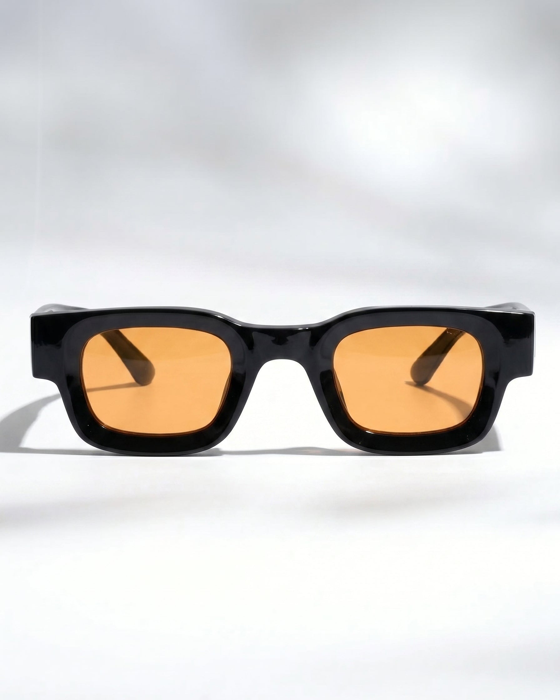 Sunglasses with black frame and orange lenses on a white background
