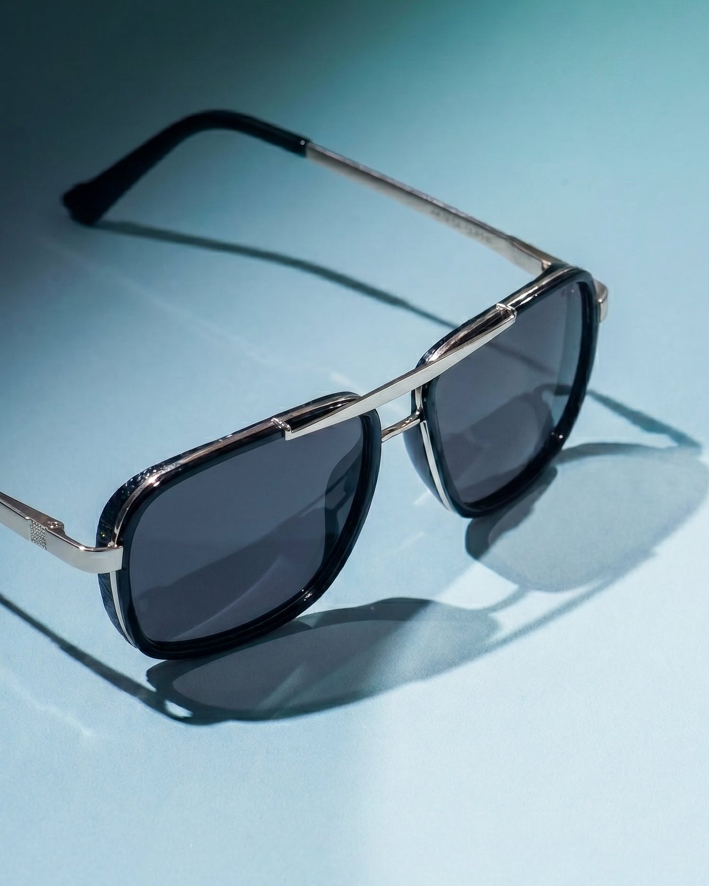 Sunglasses with dark lenses and silver frame on a light blue background