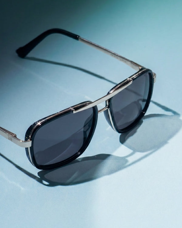 Sunglasses with dark lenses and silver frame on a light blue background