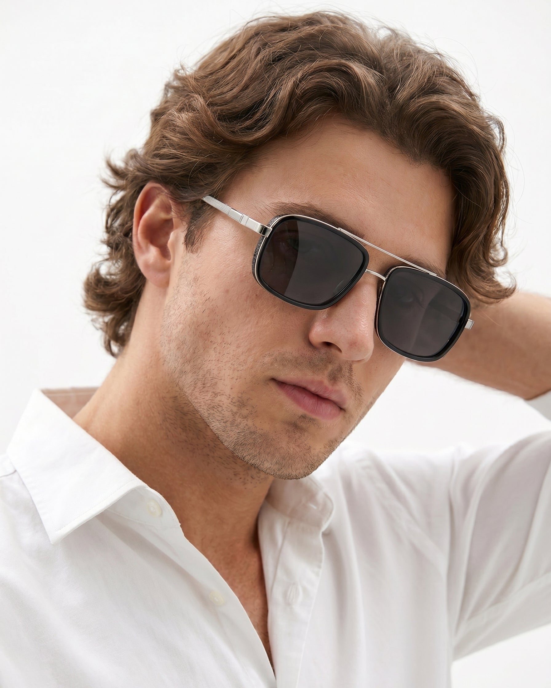 Man wearing sunglasses and a white shirt against a light background