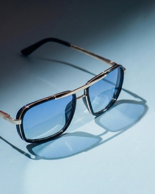 Sunglasses with gold frame and blue lenses on a light blue background