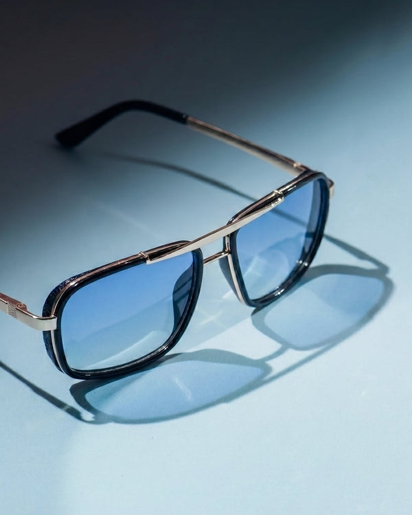 Sunglasses with gold frame and blue lenses on a light blue background